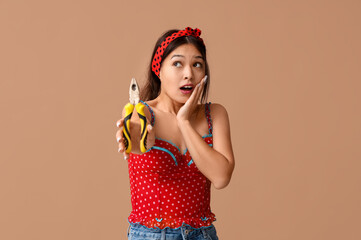 Shocked young Asian pin-up woman with pliers on brown background