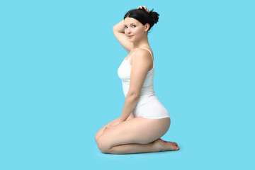 Obraz premium Body positive woman in underwear sitting on blue background