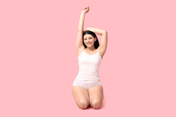 Body positive woman in underwear smiling on pink background