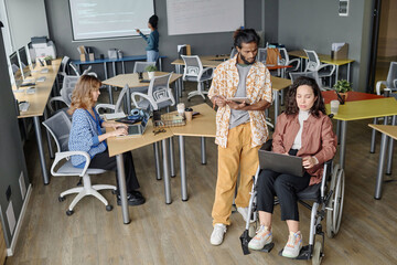Diverse group of young programmers working side by side in modern spacious office
