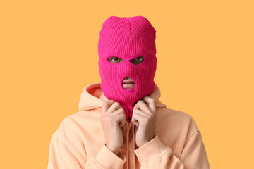 Handsome young man in balaclava on yellow background