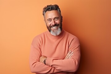 Portrait of a happy mature man with arms folded over orange background
