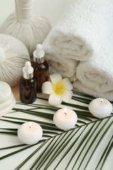 Fototapeta na wymiar Composition with different spa products, burning candles and plumeria flower on white table