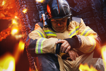 Sad fireman sits next to burning house, hard profession of rescue services. Concept psychological...