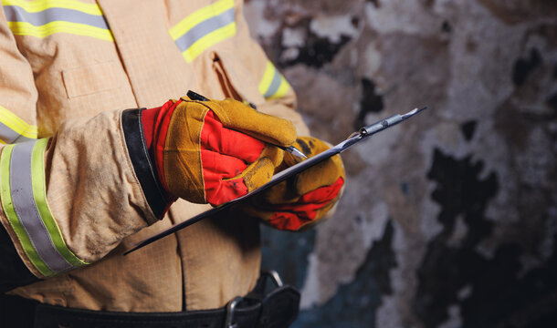 Fireman inspector conducts investigation to determine circumstances of fire in house and uses clipboard for report incident. Concept Insurance payments and checklist