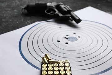 Shooting target, handgun and bullets on table