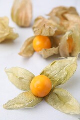 Ripe physalis fruits with calyxes on white marble table, closeup