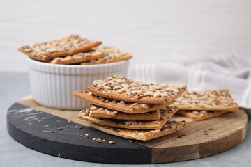 Cereal crackers with flax, sunflower and sesame seeds on grey table, closeup
