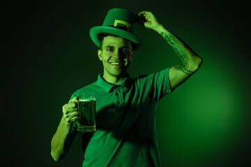 Happy young tattooed man with beer on dark green background. St. Patrick's Day