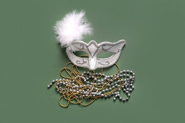 Carnival mask with beads for Mardi Gras celebration on green background