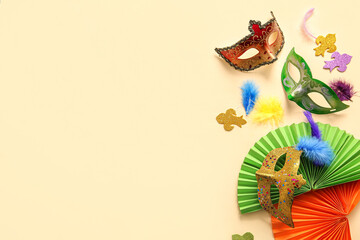 Carnival masks with feathers and paper fans for Mardi Gras celebration on beige background
