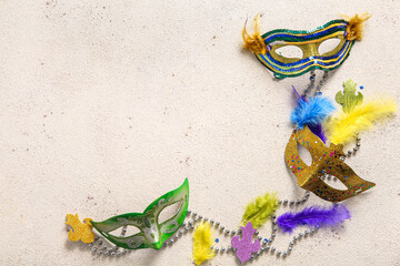 Carnival masks with feathers and beads for Mardi Gras celebration on light grunge background