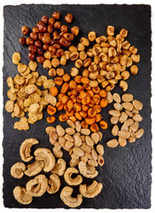 Snack mix: roasted giant corn, fried almonds, pork rind on stone background.