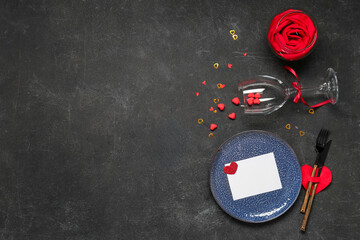 Beautiful table setting for Valentine's Day with blank card and hearts on black grunge background