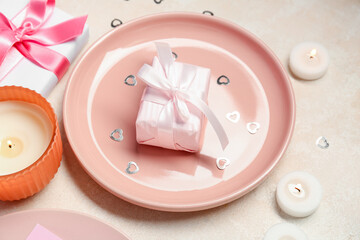 Beautiful table setting for Valentine's Day with gifts, hearts and candles on beige grunge background