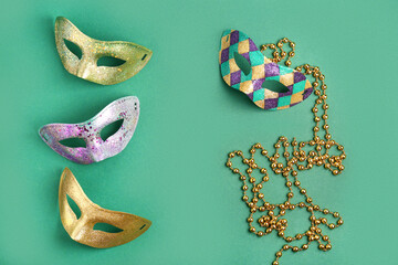 Shiny carnival masks with beads for Mardi Gras celebration on green background
