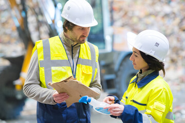 refuse site workers holding carboard and a plastic spray bottle