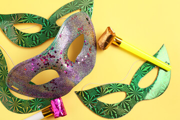 Carnival masks with party horns for Mardi Gras celebration on yellow background