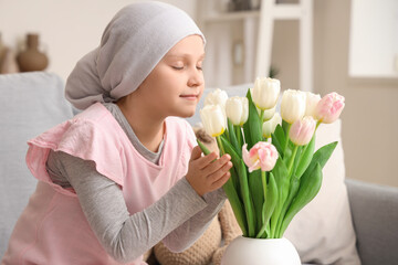 Little girl after chemotherapy with tulips at home, closeup. International Childhood Cancer Day