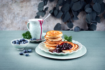 Traditional American pancakes with blueberry fruits and jam served as close-up on a Nordic design plate