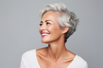 Portrait of a beautiful middle aged woman with short gray hair, over grey background