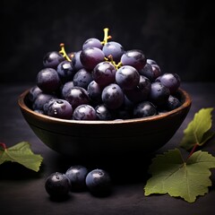 Blue grapes in a plate. Dark grapes in porcelain plate on a black background. Bunch of grapes with leaves. Summer berries. Sweet delicious grapes.