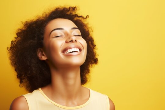 young happy african american woman with curly hair on yellow background