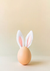 an egg with bunny ears in the center, light beige background, Easter card concept 