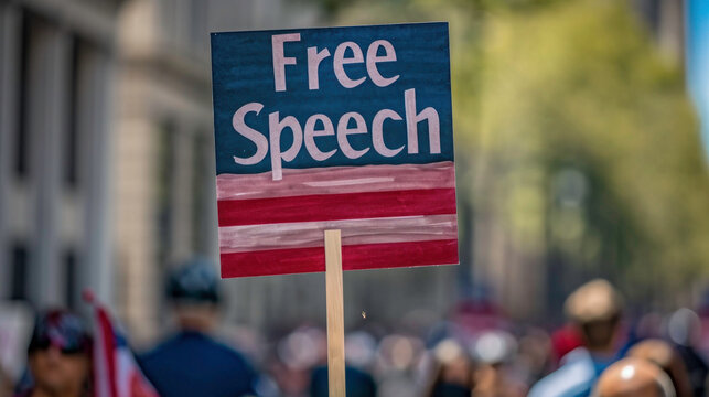 A 'Free Speech' sign held high amidst a crowd, the American flag design echoing the nation's commitment to this fundamental right.