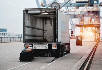Naklejka premium Cargo Truck In The Trade Port. Heavy-Duty Commercial Vehicle For Supply Delivery.. Semitrailer During Loading Of The Cargo. Commercial Vehicle For Shipping And Post Delivery
