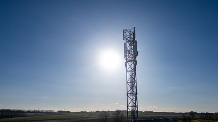 This photograph captures a solitary telecommunication tower standing tall against a bright blue...