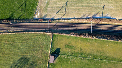 This image provides an aerial perspective of railway tracks cutting through agricultural fields....