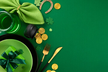Irish delight: Celebrating St. Patrick's Day in style. Top view shot of plates, cutlery, napkin, leprechaun hat, green beer, pots, coins, present, horseshoe, clovers on green background with ad zone - obrazy, fototapety, plakaty