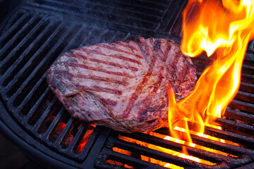 Traditional American barbecue flanksteak steak as close-up on a charcoal grill with fire