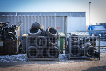 containers filled with old tires and car parts in the yard of a car repair shop
