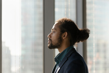 Business vision. Side view portrait of black businessman ceo look at office window ponder visualize think on perspectives. Young biracial male worker in formal suit plan successful career. Copy space
