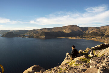 Man sitting on a viewpoint in Copacabana with a beautiful view of Lake Titicaca
