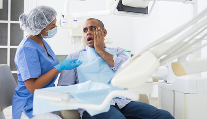 Man in medical chair complains of toothache to dentist