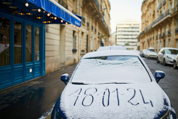 Car window covered with snow with date of snowfall written on it