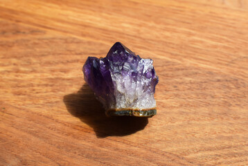 Beautiful dark purple druse with amethyst crystals on a wooden background. Magical semi-precious...