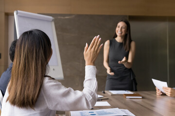 Back view of young employee woman raising hand, asking question on business seminar meeting,...