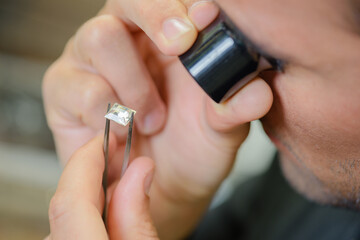 Man looking at precious stone through magnifying eyepiece