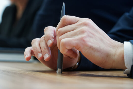 A man holds a fountain pen while sitting at a table during a business meeting or negotiation. Anonymous, unrecognizable, without a face. Photo. Selective focus