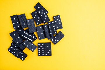 Black domino on a yellow background. Domino effect concept. Business, risk, management and finance concept