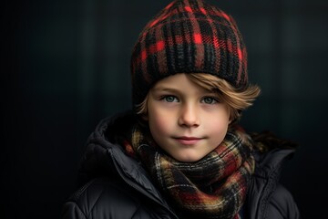 A portrait of a cute little boy wearing a warm hat and scarf. Winter fashion.