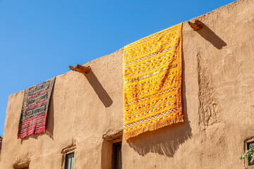 Ornated arabic carpets hanging from the roof of traditional mud houses, Al Ula, Medina province,...