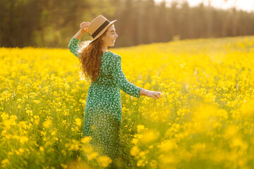 Beautiful woman walking flowering field gently touch yellow flowers. Nature, fashion,  summer...