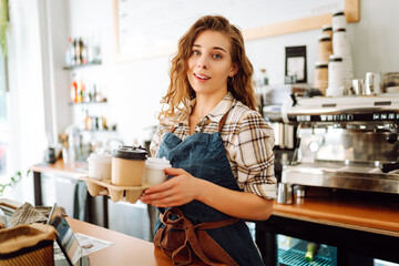 Portrait of beautiful young barista woman serving coffee with a big smile. Small business owner, food and drink industry concept.