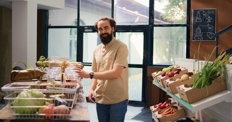 Young client shopping in eco supermarket, looking at fresh natural fruits and veggies locally grown from farms. Man visiting bio zero waste organic shop to buy additives free pasta or grains.