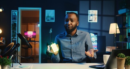 African american tech content creator filming technology review of mini RGB lights device...